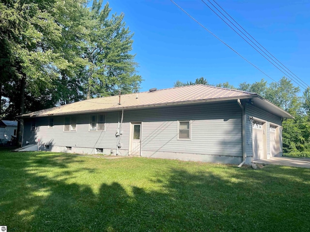 rear view of property featuring a garage and a yard