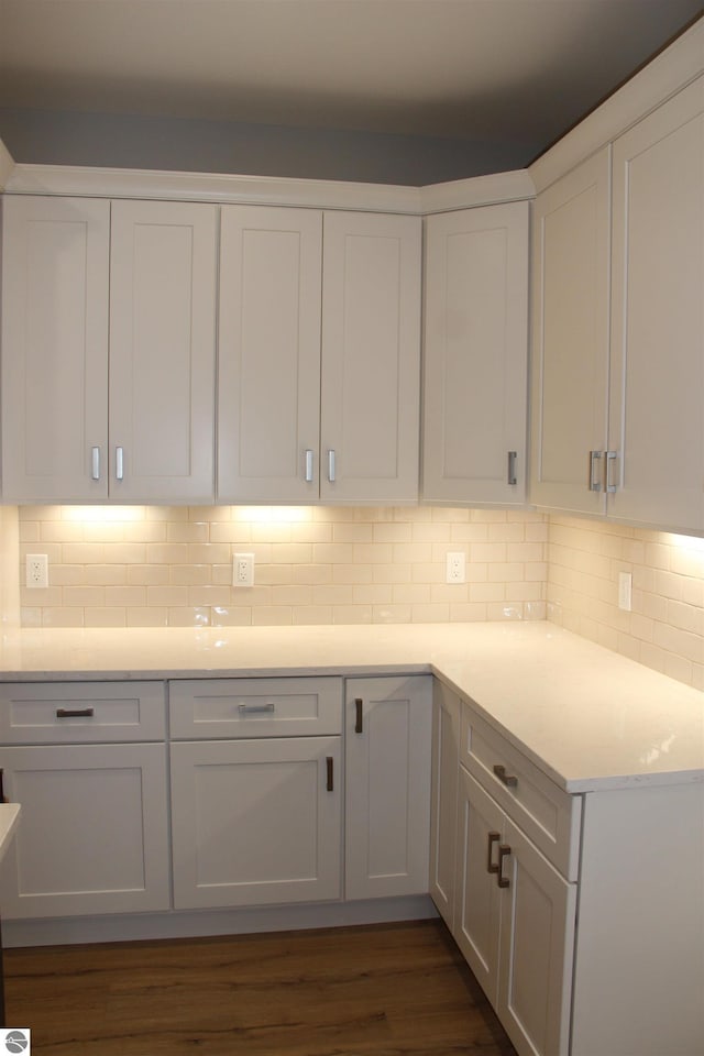 kitchen featuring decorative backsplash, dark wood finished floors, light countertops, and white cabinetry