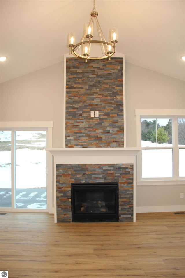 room details featuring a stone fireplace, an inviting chandelier, baseboards, and wood finished floors