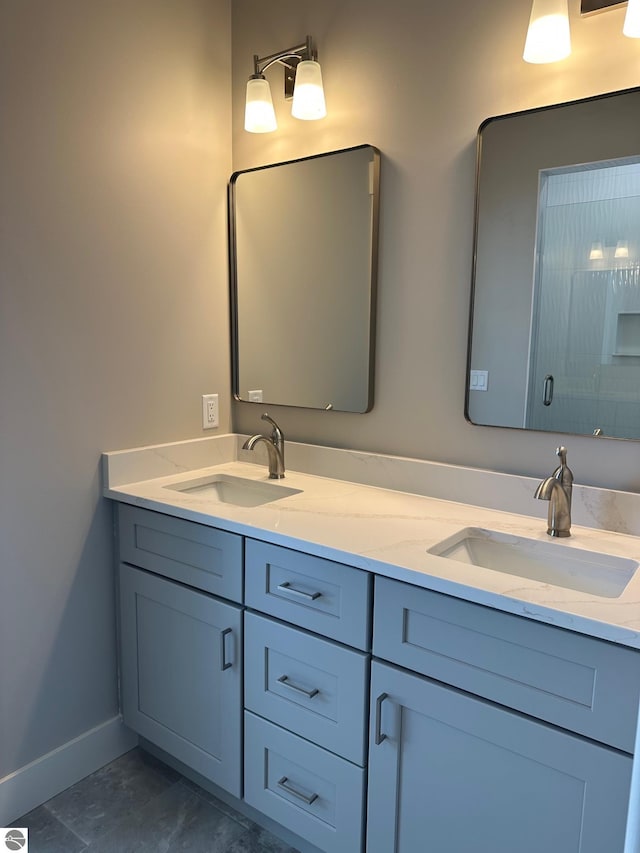 bathroom featuring double vanity, baseboards, and a sink