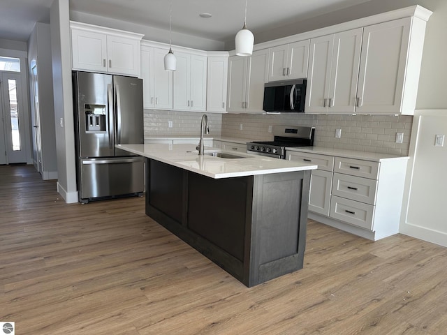 kitchen featuring a sink, light countertops, appliances with stainless steel finishes, white cabinetry, and light wood-type flooring