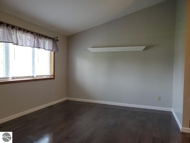 empty room with vaulted ceiling and dark hardwood / wood-style floors