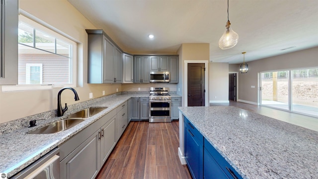 kitchen with stainless steel appliances, dark wood-type flooring, plenty of natural light, and light stone countertops