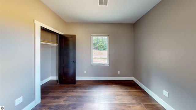 unfurnished bedroom featuring dark hardwood / wood-style flooring and a closet