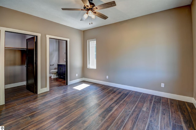 unfurnished bedroom featuring ceiling fan, ensuite bath, dark wood-type flooring, and a closet