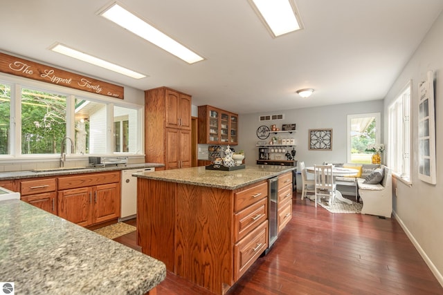 kitchen with beverage cooler, dishwasher, light stone counters, a center island, and dark hardwood / wood-style floors