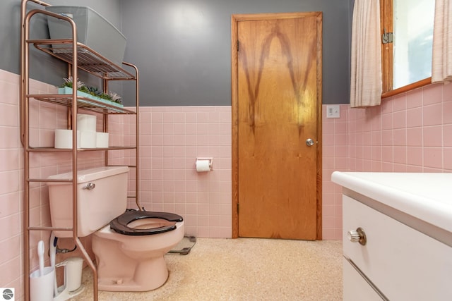 bathroom with tile walls, toilet, and vanity