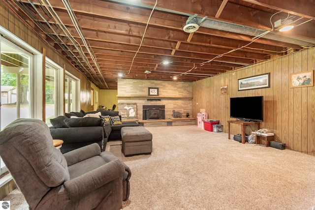 carpeted living room with a fireplace and wood walls