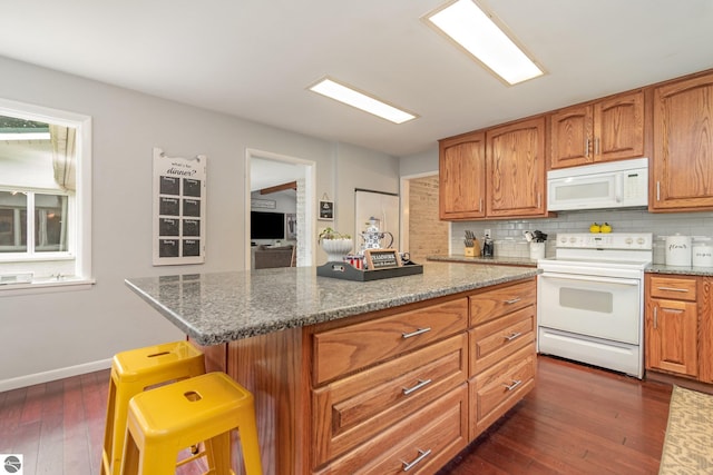 kitchen featuring white appliances, a breakfast bar, dark hardwood / wood-style flooring, backsplash, and a kitchen island