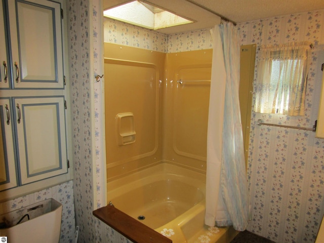 bathroom featuring shower / bath combo, a skylight, and wallpapered walls