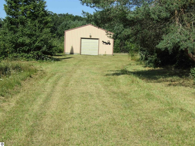 view of yard featuring driveway, an outdoor structure, and a detached garage