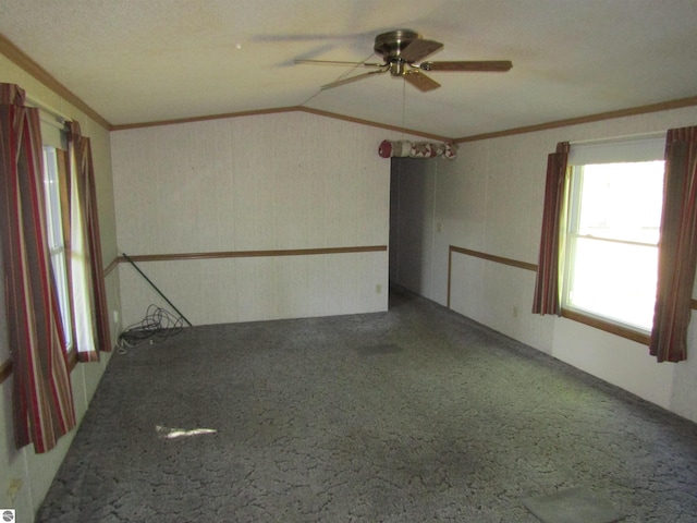 empty room with ornamental molding, carpet flooring, vaulted ceiling, and a ceiling fan