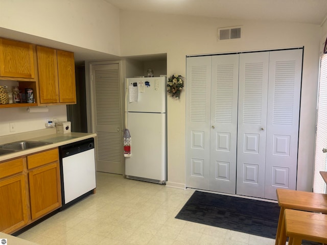 kitchen with sink, vaulted ceiling, white appliances, and light tile patterned floors