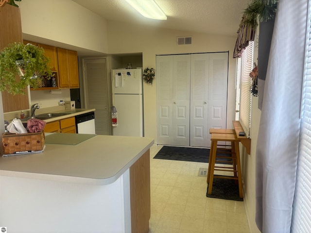 kitchen with sink, white appliances, light tile patterned floors, kitchen peninsula, and lofted ceiling