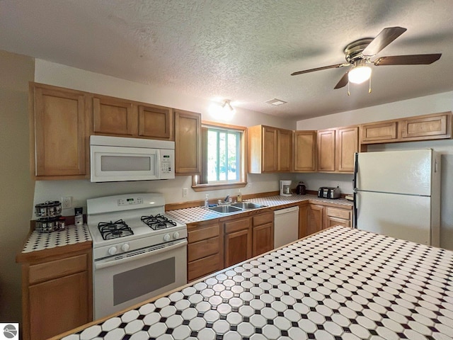 kitchen featuring tile countertops, sink, white appliances, ceiling fan, and a textured ceiling