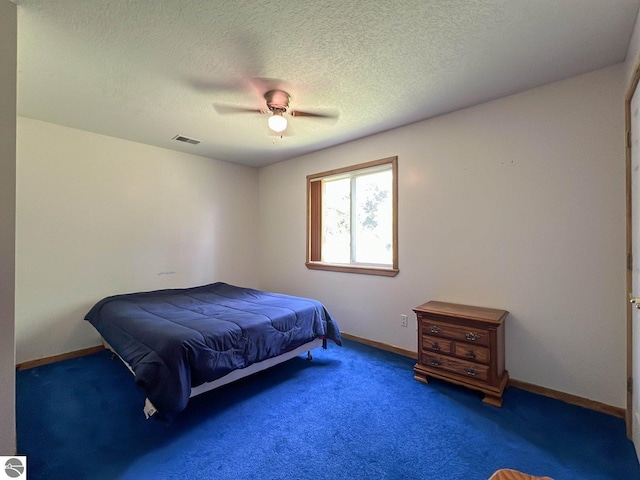 bedroom featuring ceiling fan, dark carpet, and a textured ceiling