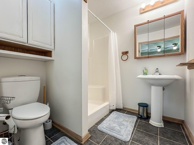 bathroom with sink, toilet, tile patterned flooring, and a textured ceiling