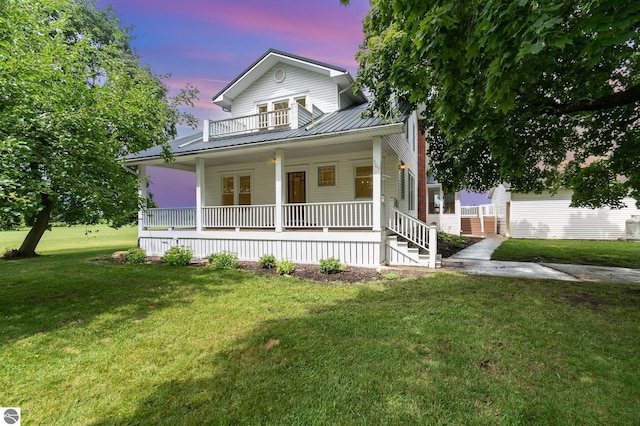 view of front facade featuring a lawn, a balcony, and covered porch