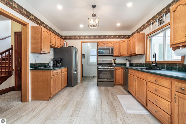 kitchen with sink, decorative light fixtures, light hardwood / wood-style flooring, appliances with stainless steel finishes, and a notable chandelier