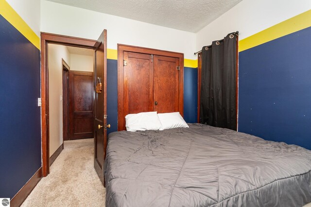 bedroom featuring a textured ceiling, a closet, and light carpet