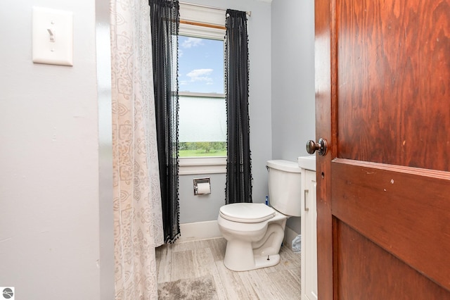 bathroom with a wealth of natural light, wood-type flooring, and toilet