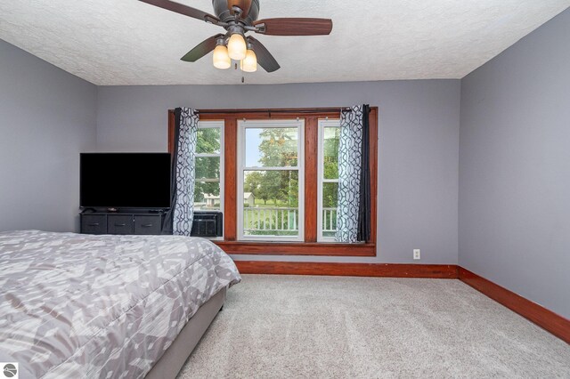 bedroom with ceiling fan, carpet flooring, and a textured ceiling