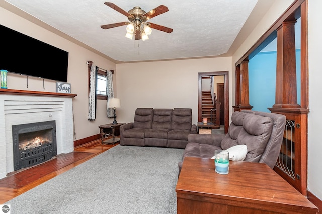 living room featuring a textured ceiling, ceiling fan, hardwood / wood-style flooring, and a brick fireplace