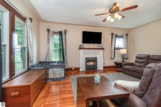 living room with ceiling fan, light hardwood / wood-style flooring, and a brick fireplace