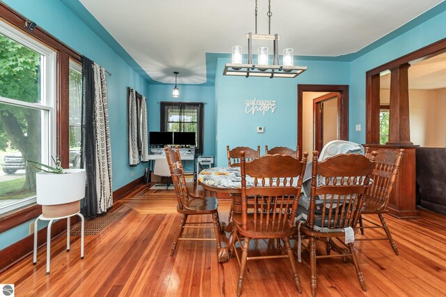 dining space with a healthy amount of sunlight, a chandelier, and wood-type flooring