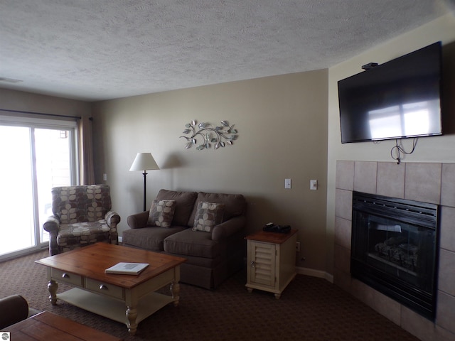 living room featuring carpet, a textured ceiling, and a tiled fireplace