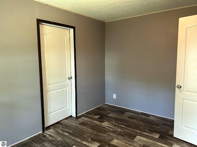 empty room featuring dark wood-style flooring and a textured ceiling