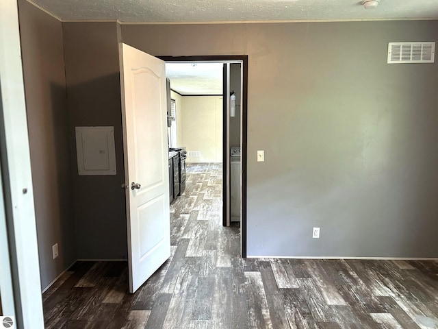 empty room with visible vents, dark wood-type flooring, a textured ceiling, and electric panel