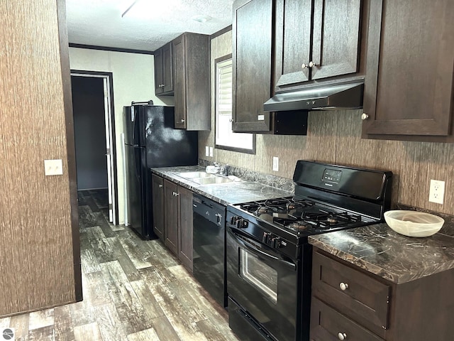 kitchen with black appliances, dark brown cabinets, a sink, and under cabinet range hood