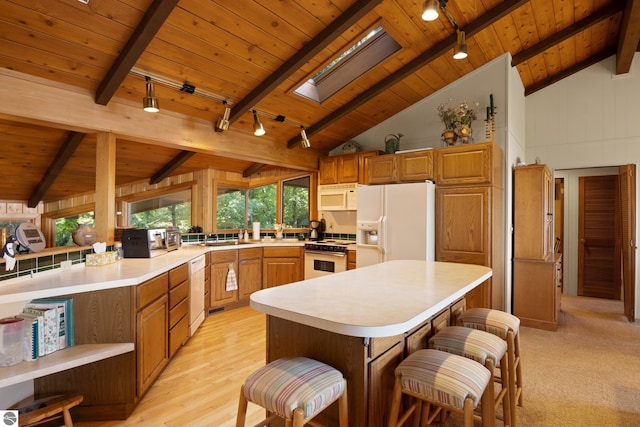 kitchen featuring white appliances, wood ceiling, a kitchen island, a breakfast bar area, and lofted ceiling with skylight