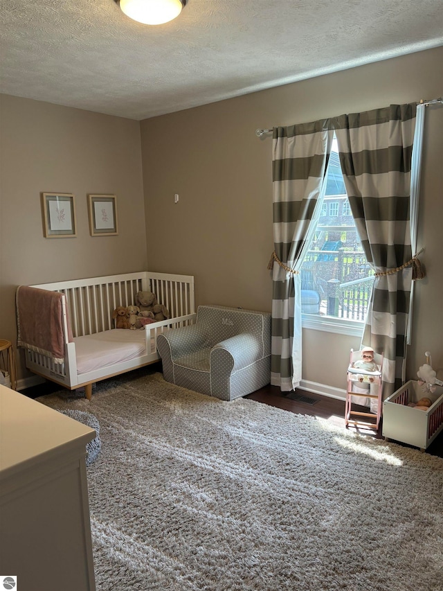 unfurnished bedroom with carpet, a crib, and a textured ceiling