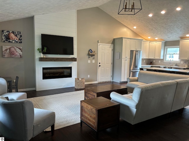 living room featuring dark hardwood / wood-style floors, high vaulted ceiling, a textured ceiling, and a fireplace