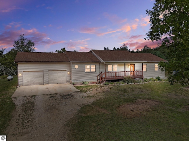 ranch-style house with a lawn, a deck, and a garage