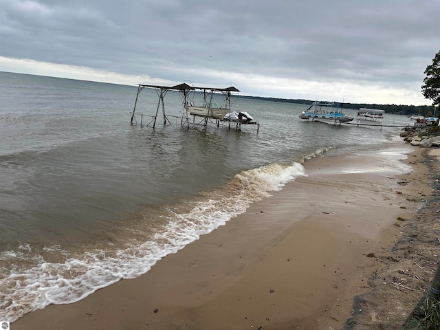 view of dock featuring a beach view and a water view