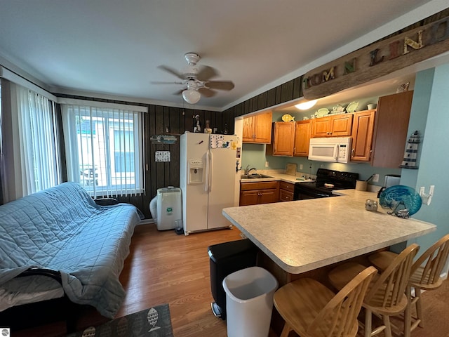 kitchen featuring sink, white appliances, light hardwood / wood-style floors, ceiling fan, and kitchen peninsula