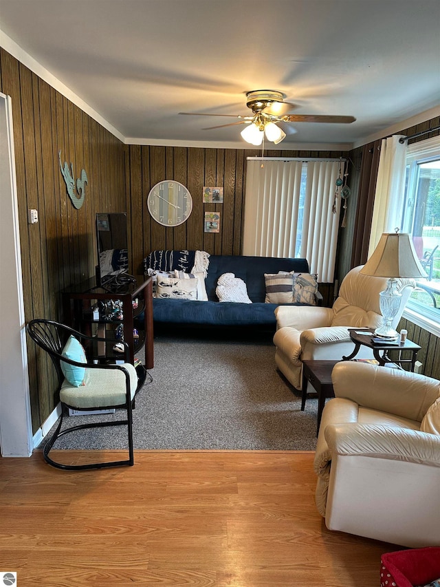 living room with hardwood / wood-style flooring, wooden walls, and ceiling fan