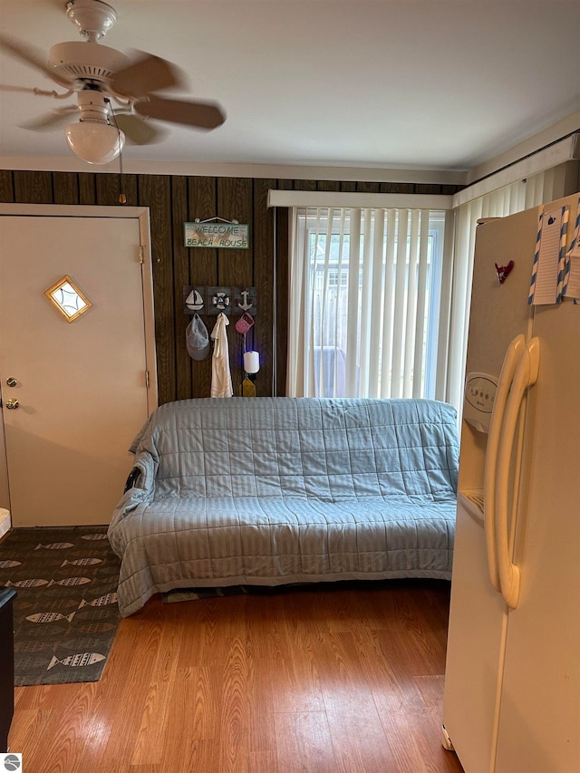 interior space with ceiling fan, white refrigerator with ice dispenser, and wood-type flooring