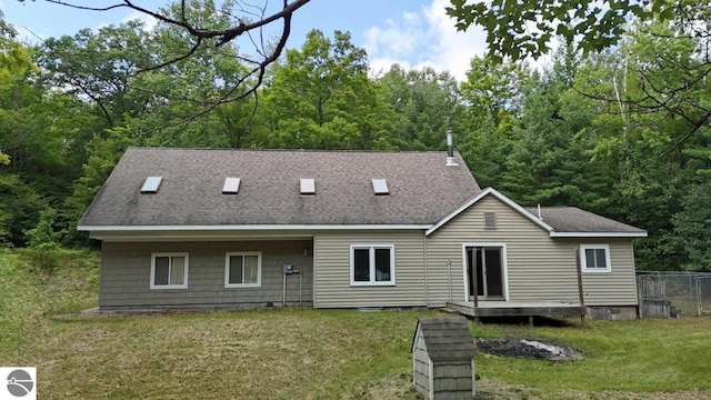 back of house featuring a shingled roof, a lawn, and fence