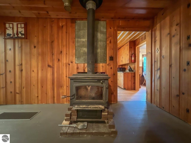 interior space with light wood-style floors, a wood stove, and wooden walls