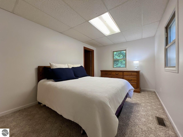 bedroom with a paneled ceiling, carpet, visible vents, and baseboards