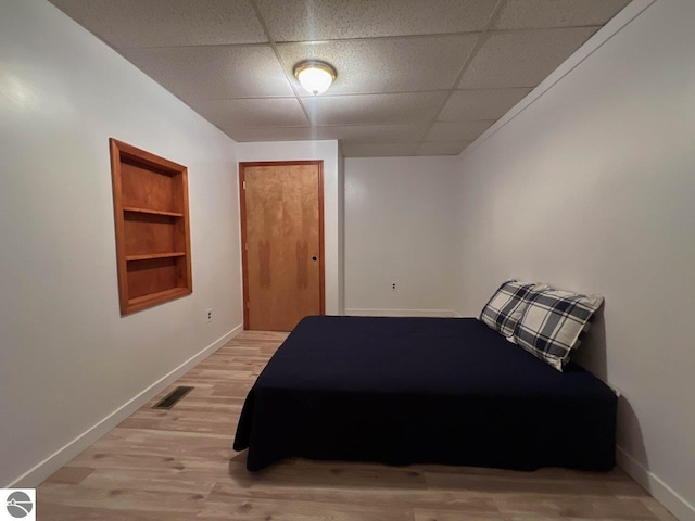 bedroom featuring a drop ceiling, visible vents, baseboards, light wood-style floors, and a closet