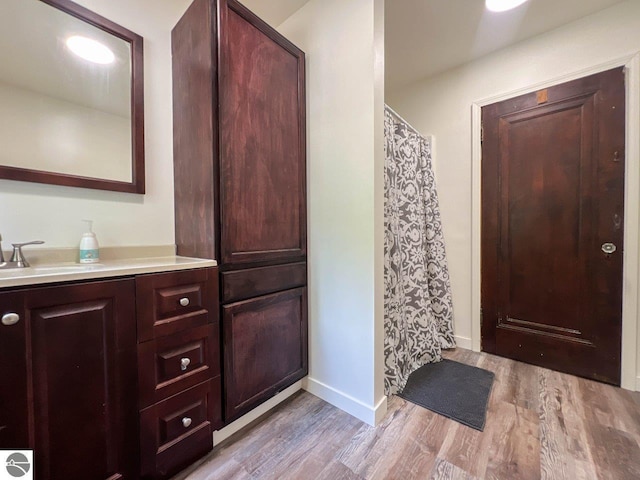 bathroom featuring baseboards, wood finished floors, and vanity