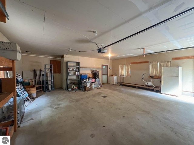 garage featuring a garage door opener and freestanding refrigerator