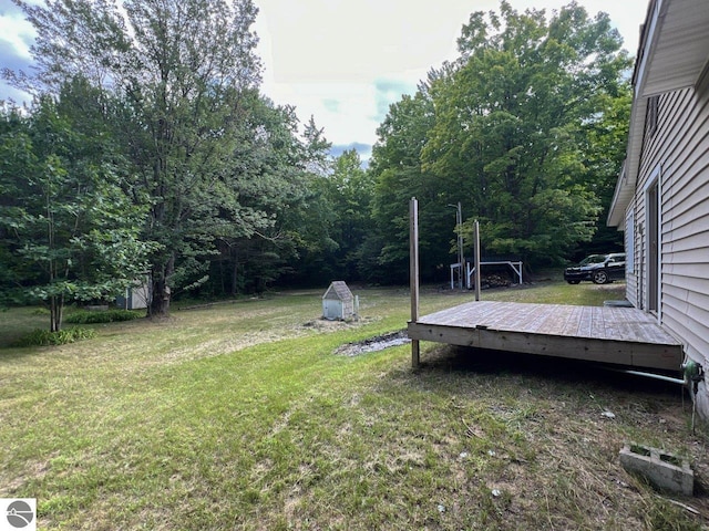 view of yard with an outdoor structure, a deck, and a storage shed