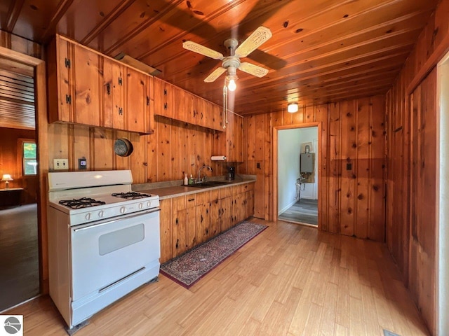 kitchen featuring brown cabinetry, white gas range oven, light countertops, and a sink