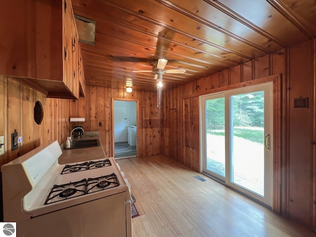 kitchen with gas range gas stove, light countertops, wood walls, a sink, and wooden ceiling